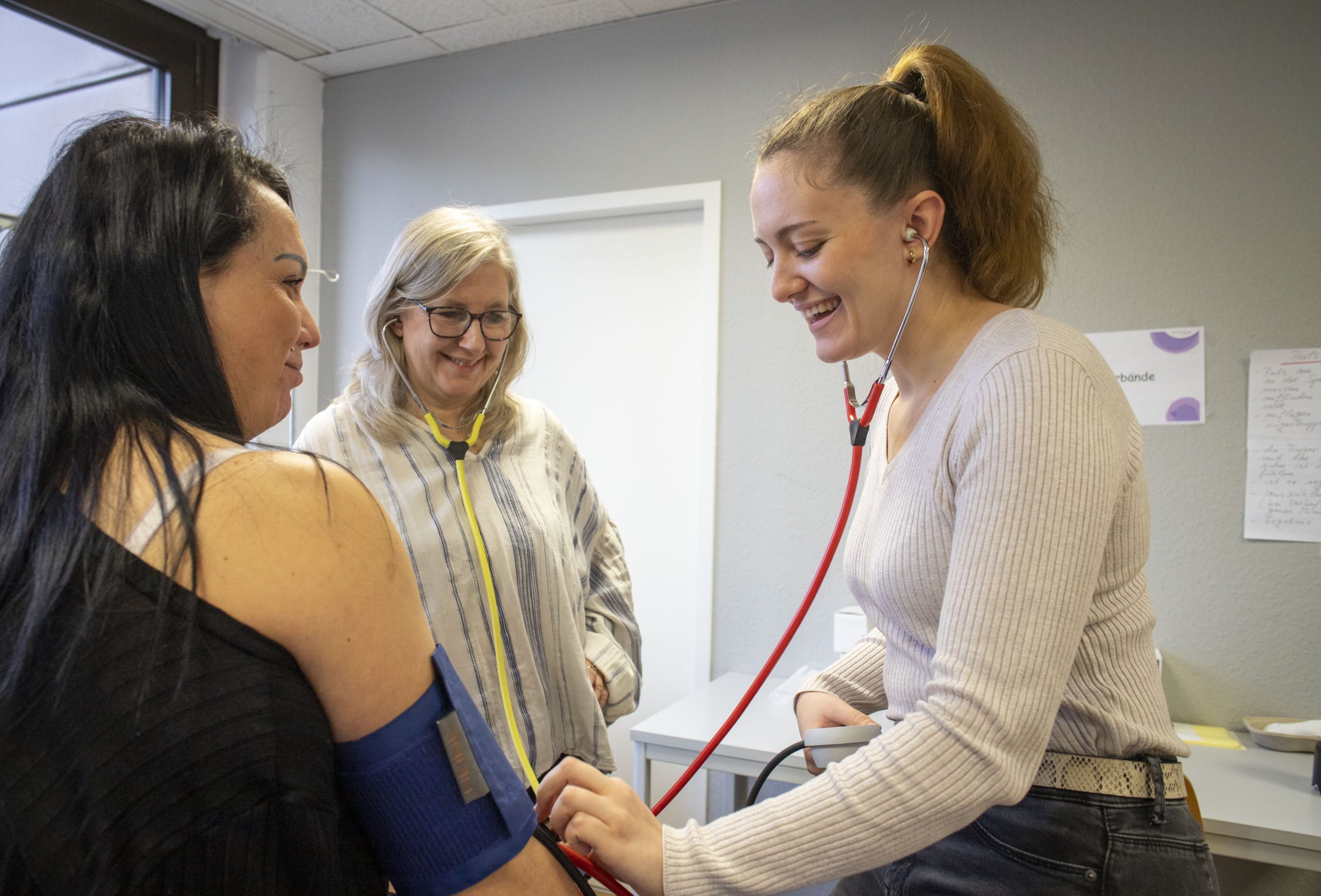 08D Die Schüler üben das Messen des Blutdrucks und das Hören des Pulses. Lehrer stehen und überwachen.